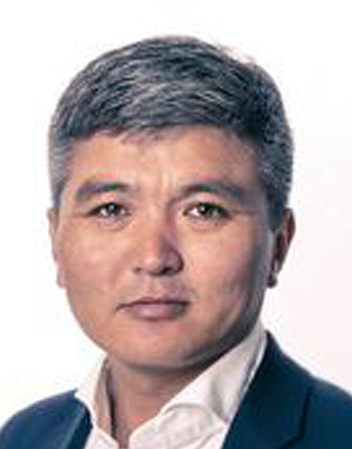 Mężczyzna w średnim wieku o azjatyckich rysach i szpakowatych włosach. Nosi granatową marynarkę.