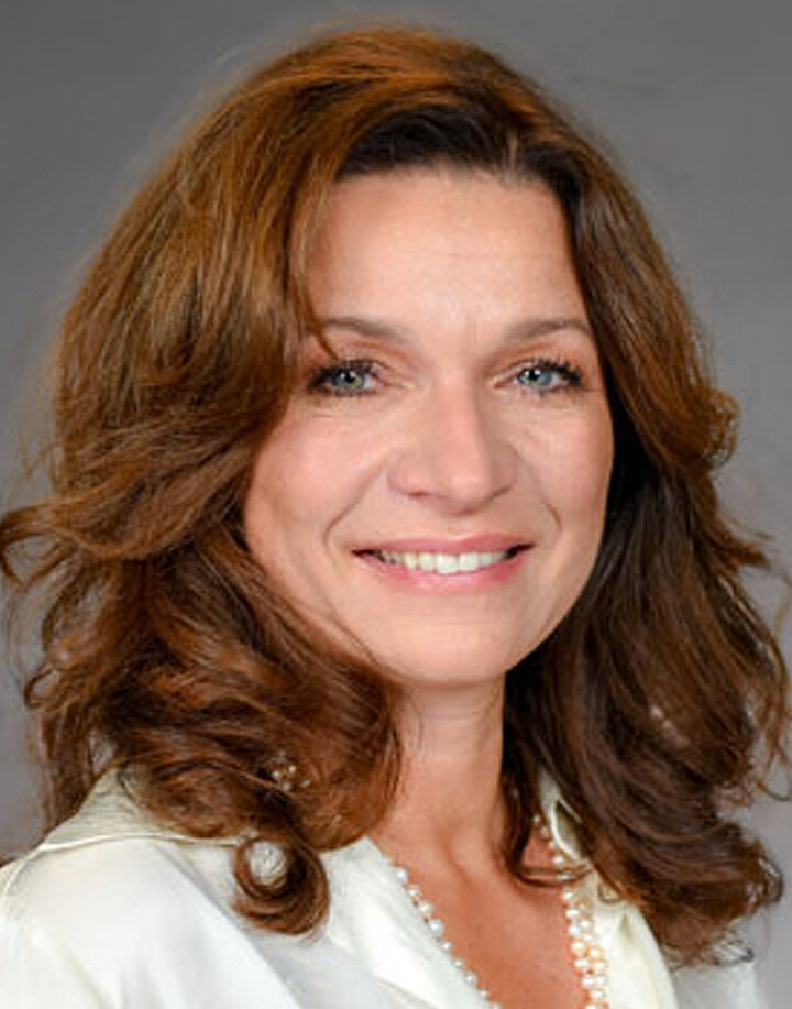 Uśmiechnięta kobieta w średnim wieku o ciemnych długich włosach. 