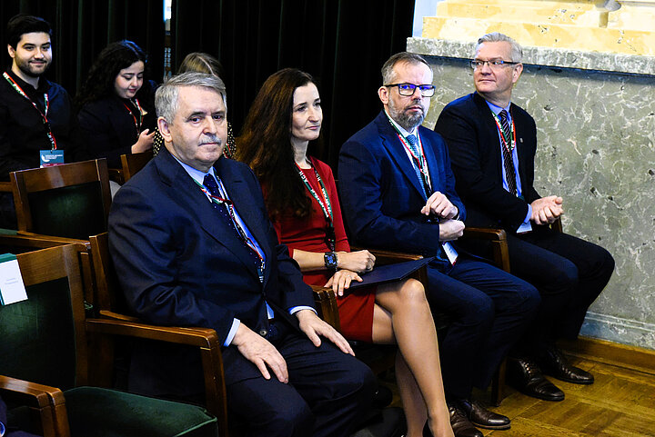 Uczestnicy siedżacy w dużej zabytkowej sali