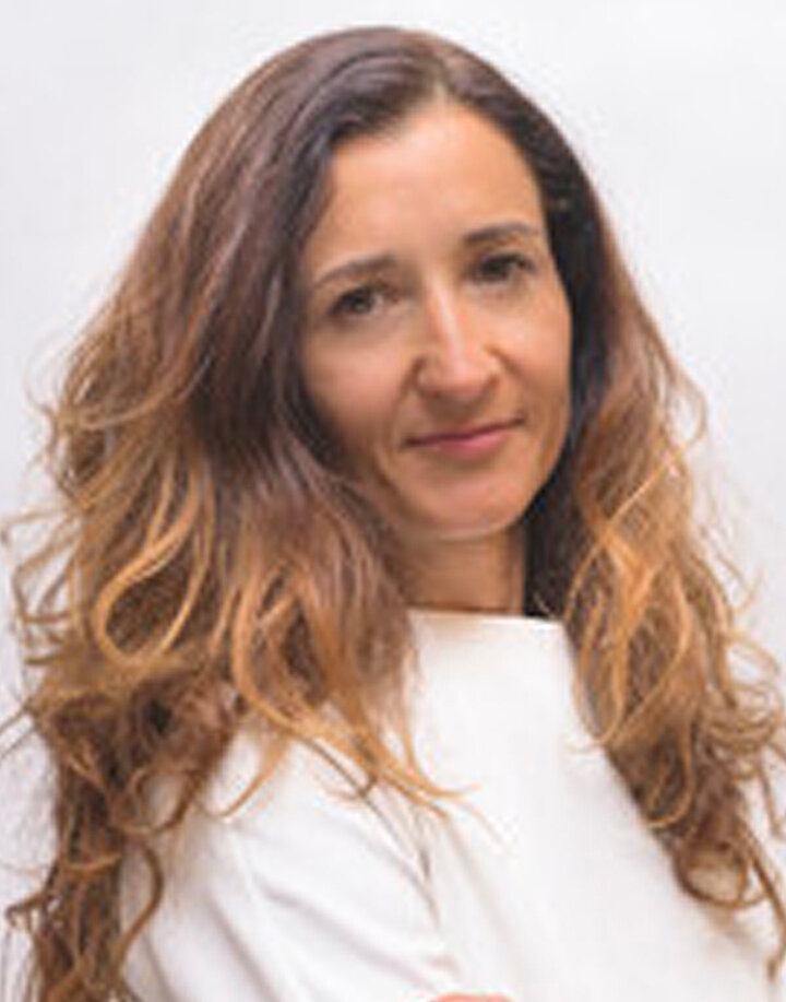 Młoda kobieta z długimi blond włosami. Nosi białą bluzkę.