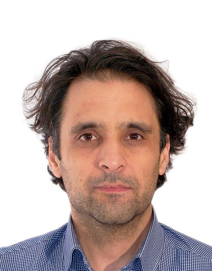 Mężczyzna w średnim wieku z ciemnymi dłuższymo włosami.