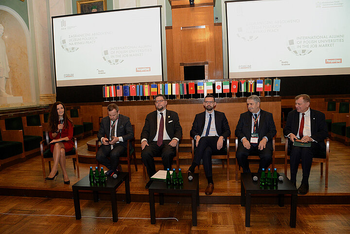 Sześcioro prelegentów siedzi w dużej zabytkowej sali.