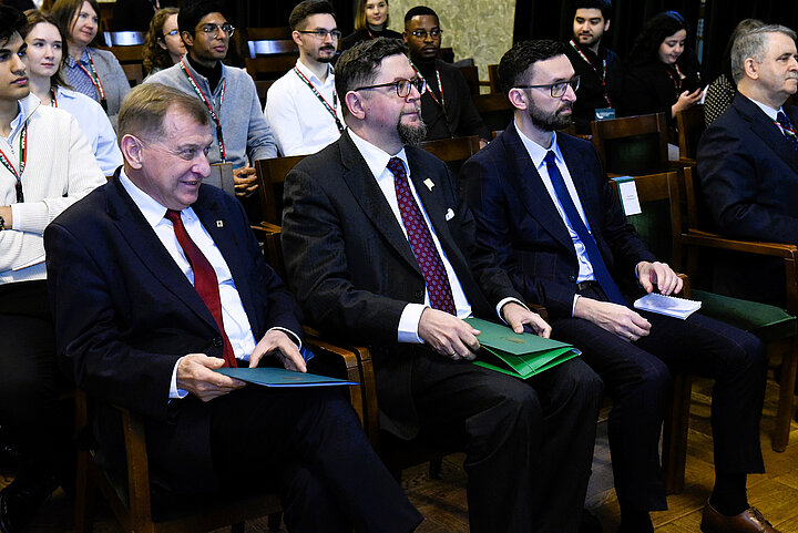 Uczestnicy siedżacy w dużej zabytkowej sali