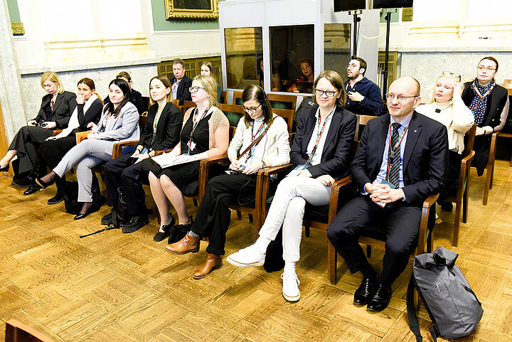 Uczestnicy siedżcy w sali.